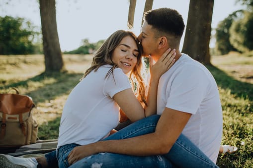 Couple having picnic in nature on blanket, enjoying sunset