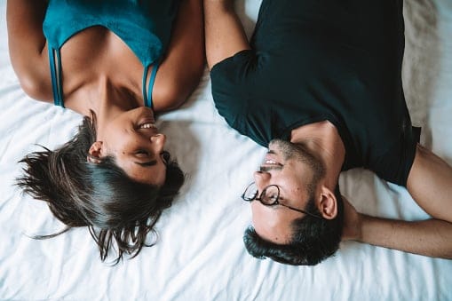 Couple laughing while lying in bed.