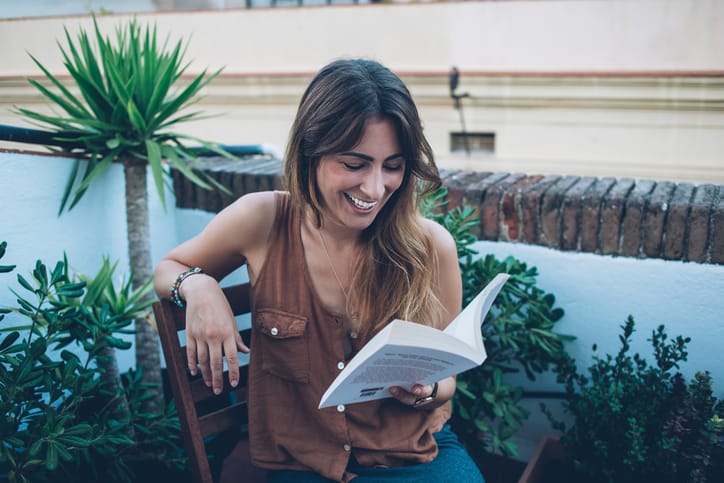 cheerful woman reading book in garden