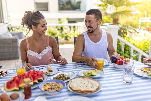 Happy couple having breakfast together on balcony.