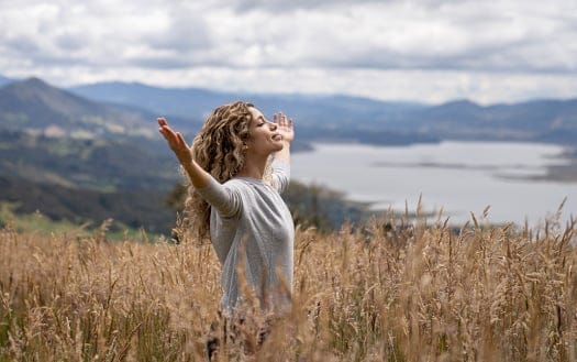 Portrait of a young Latin American woman relaxing outdoors in the countryside with arms open and eyes closed