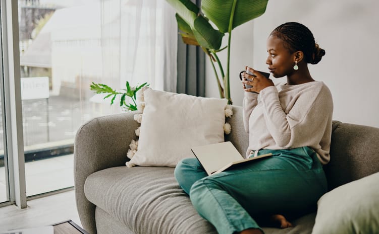 woman journaling drinking coffee couch