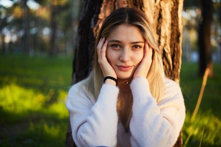 pensive woman sitting under tree in park