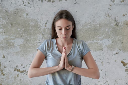Young female holding hands in namaste or prayer.