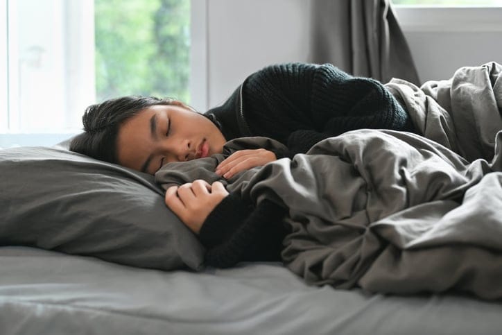 gen z girl sleeping peacefully in bed