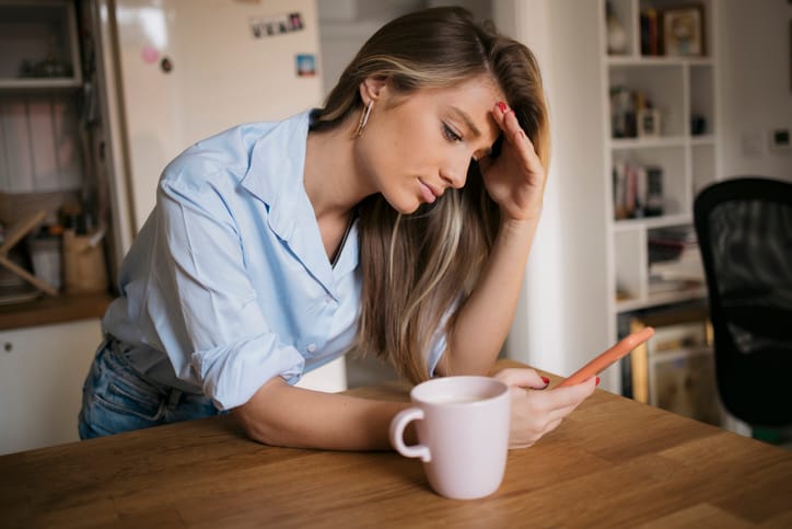 Upset woman drinking coffee in kitchen.