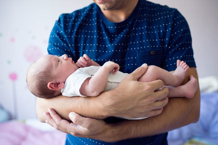 Dad cradling newborn in his arms.