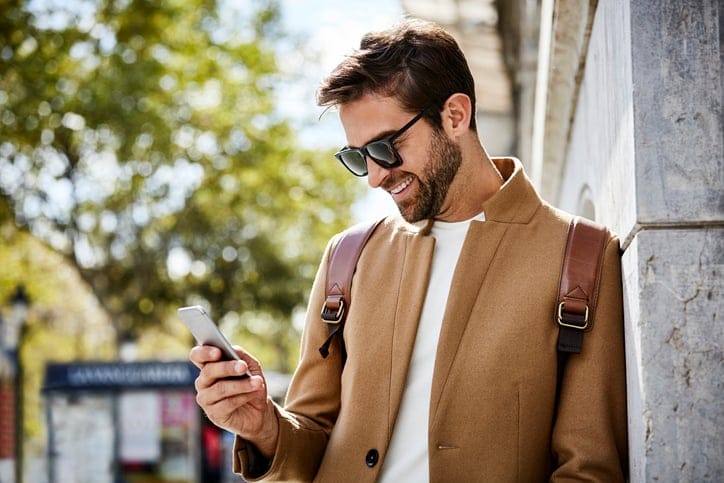 Man texting on the sidewalk.