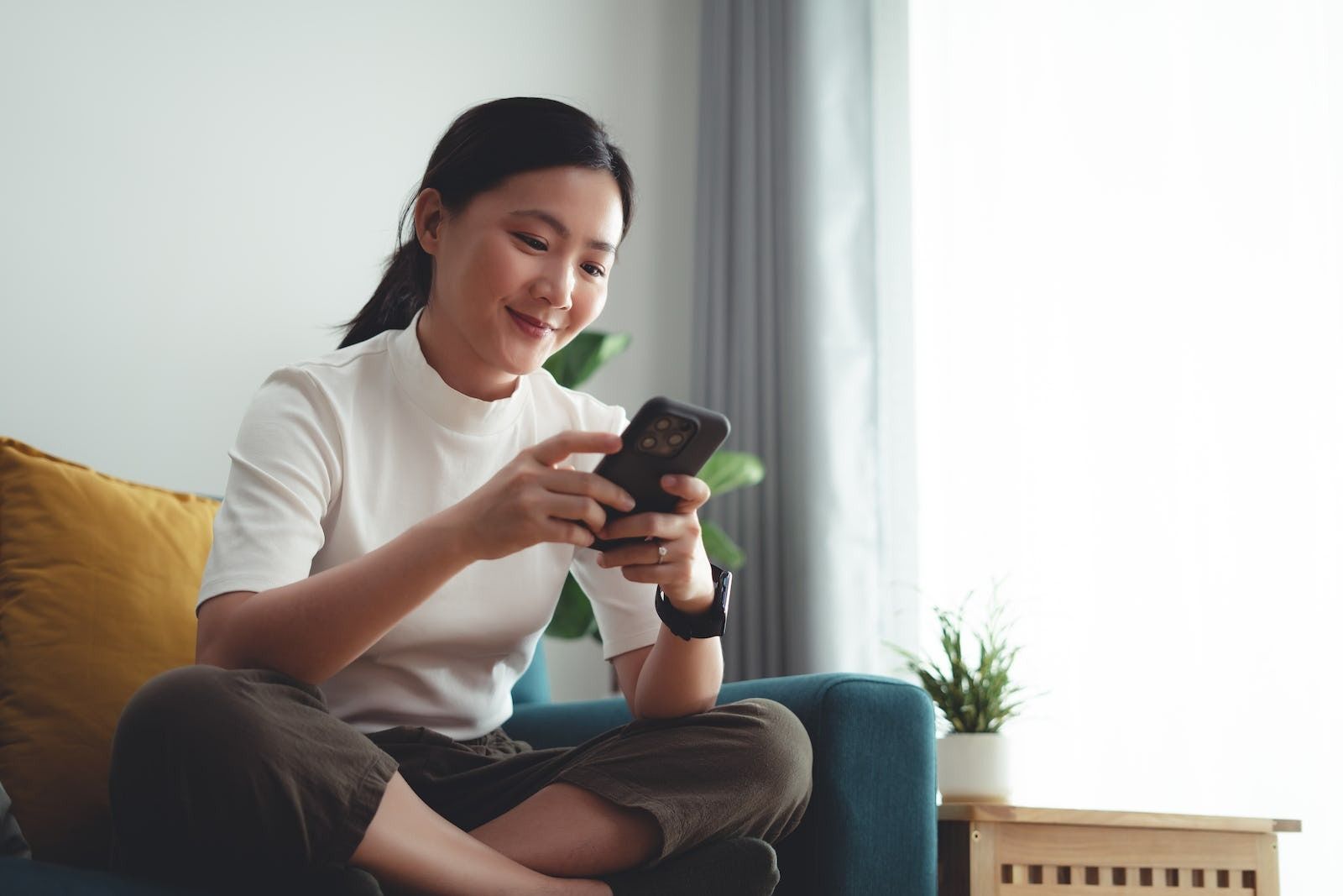 woman smiling while texting on couch