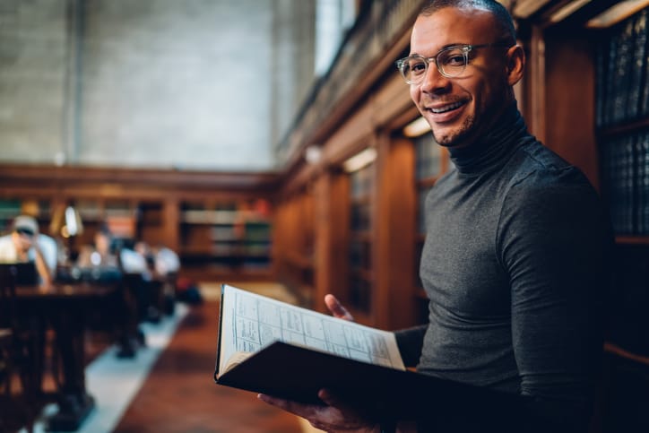 smiling man reading at library