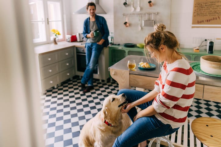 Couple with dog in kitchen.