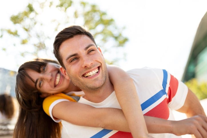 couple grinning outdoors on sunny day