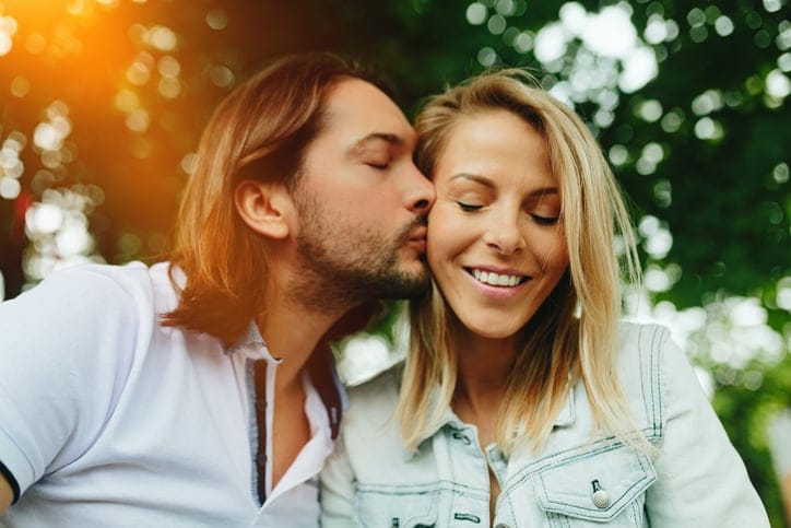 man kissing woman's cheek