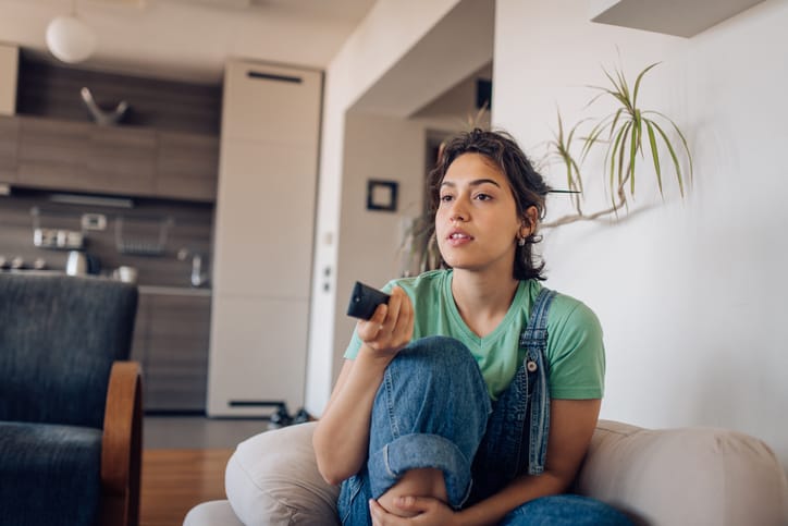 woman flicking through TV channels with remote