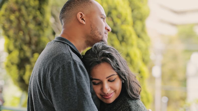 couple embracing outdoors by greenery