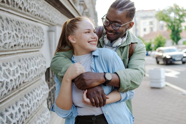 multiracial couple hugging on street