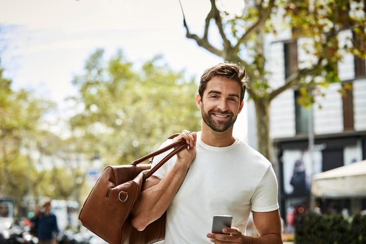 Businessman carrying his bag and holding smart phone.