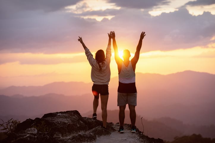 Happy couple at sunset on mountain top.