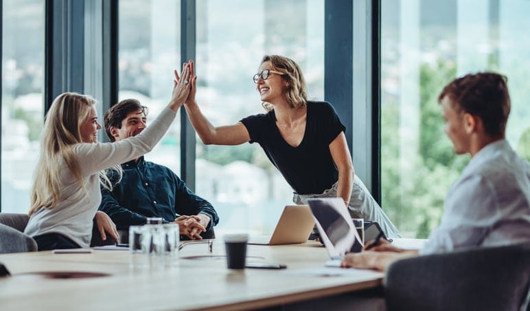 Female professional giving a high five to her colleagues.