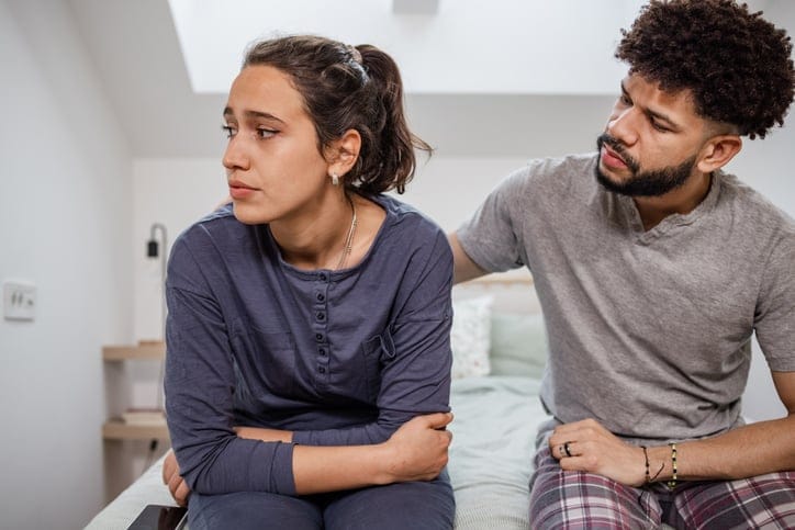 Unhappy couple sitting on bed.