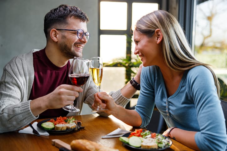 Cheerful couple toasting with alcohol during a meal in dining room.