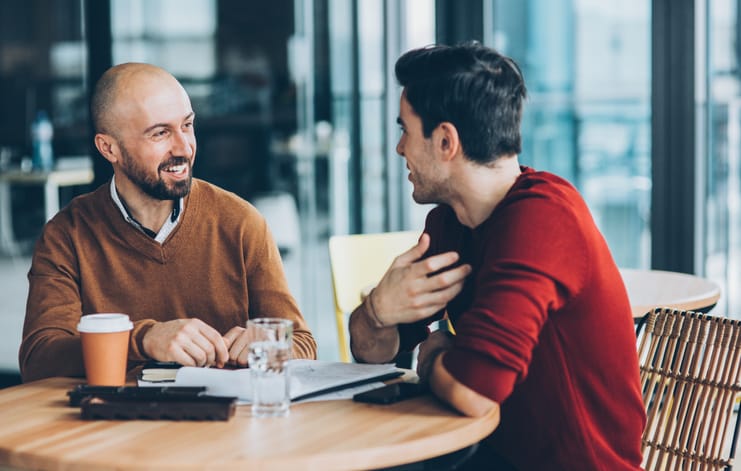 Two guys chatting at a cafe.