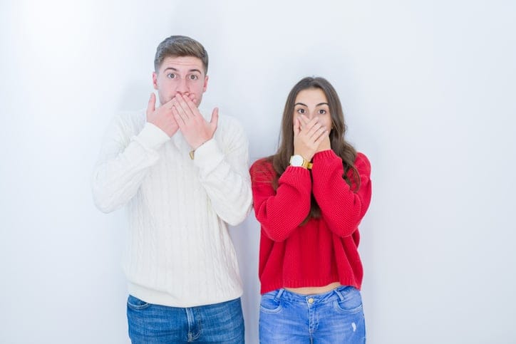Young couple covering mouth with hands.