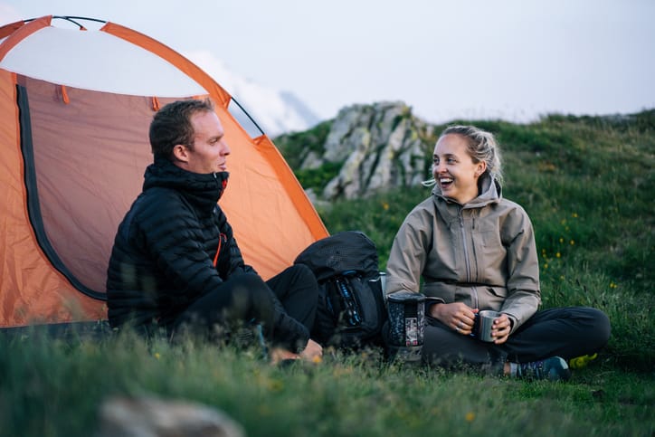 Friends relax outside tent at sunrise.