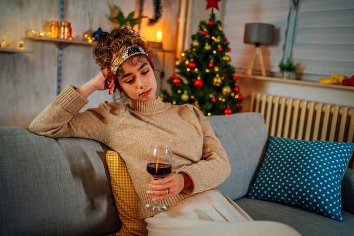 Sad woman on the couch alone at Christmas.