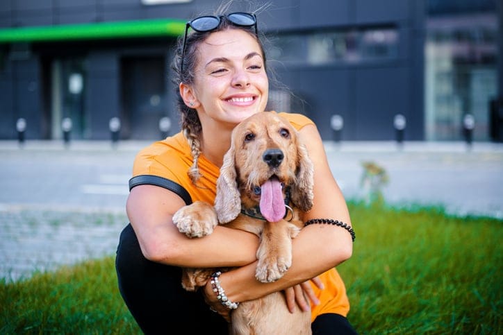 Cute girl and her dog spending day together and having fun in the public park