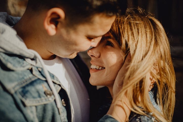 Portrait of a happy young Caucasian couple embracing and looking at each other face to face.