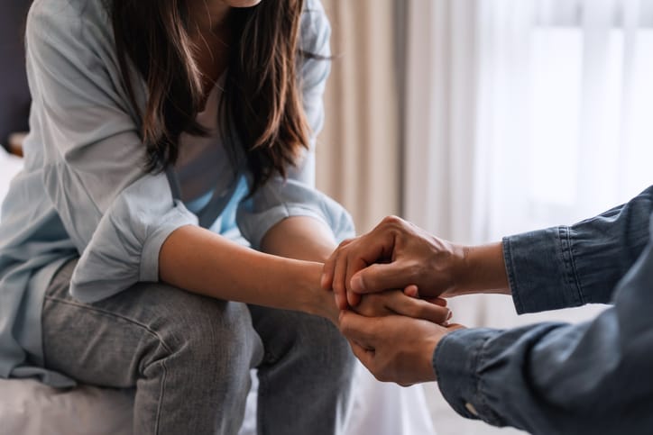 man and woman holding hands in supportive motion