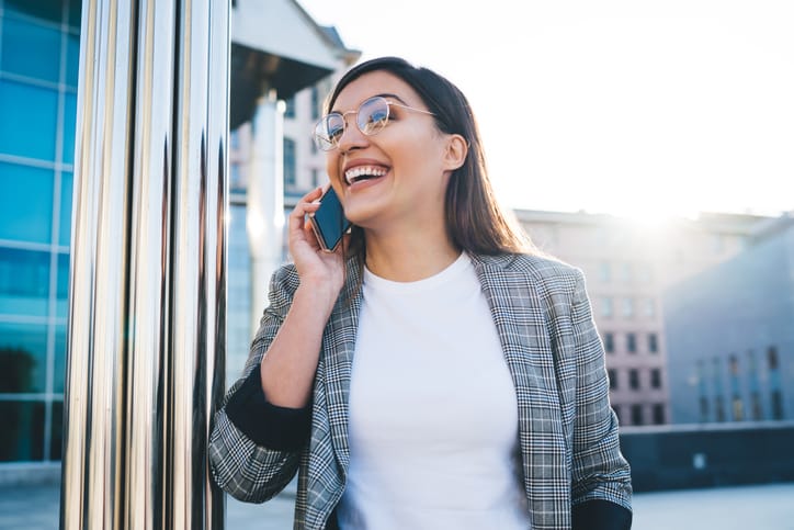 smiling woman talking on phone while walking