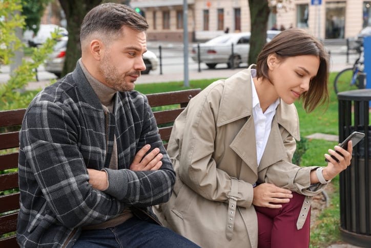 woman texting on phone while boyfriend looks