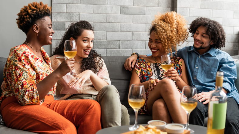 Friends chat on the couch over wine.
