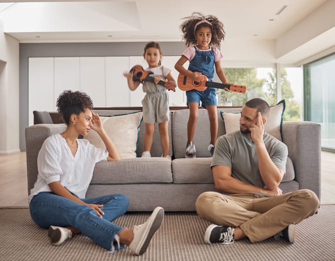 Stress, family and energy with kids playing music on a guitar in the living room at home while giving mom and dad a headache. Mental health, children and tired with a girl and sister causing chaos