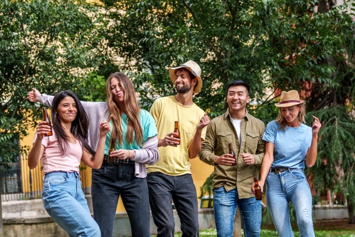 Group of friends laughing at a sunny outdoor gathering.