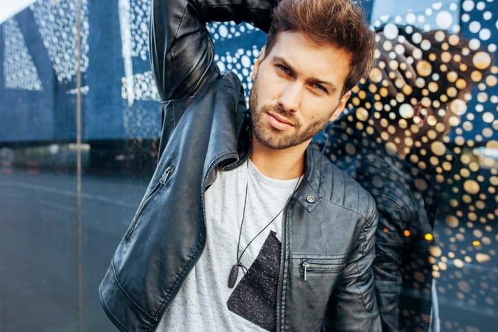 Young stylish man posing in casual wear over glass wall