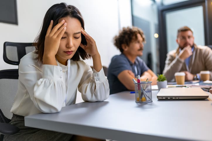 Young asian business woman having headache in the office while having a meeting