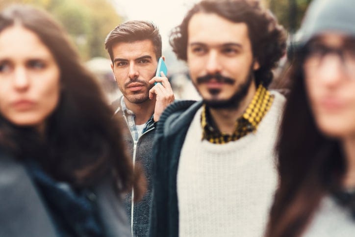 A man talking on the phone in a crowd.