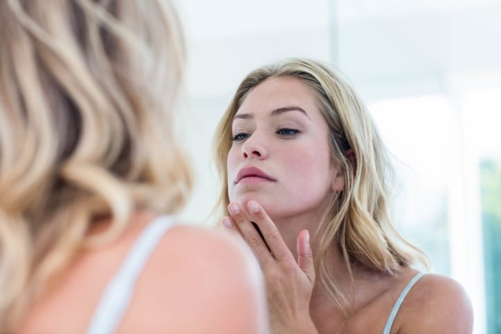 Young woman looking at herself in the bathroom mirror,