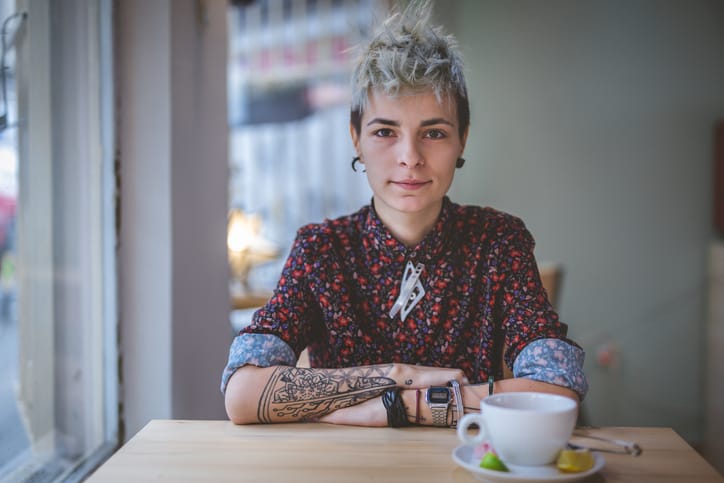 Young and lovely gender blend woman, enjoying a cup of coffee at the cafe.
