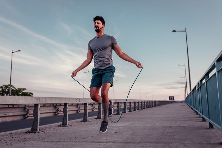 Young man jumping rope outside.