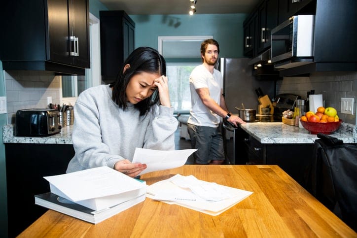 Stressed couple figuring out bills in kitchen.