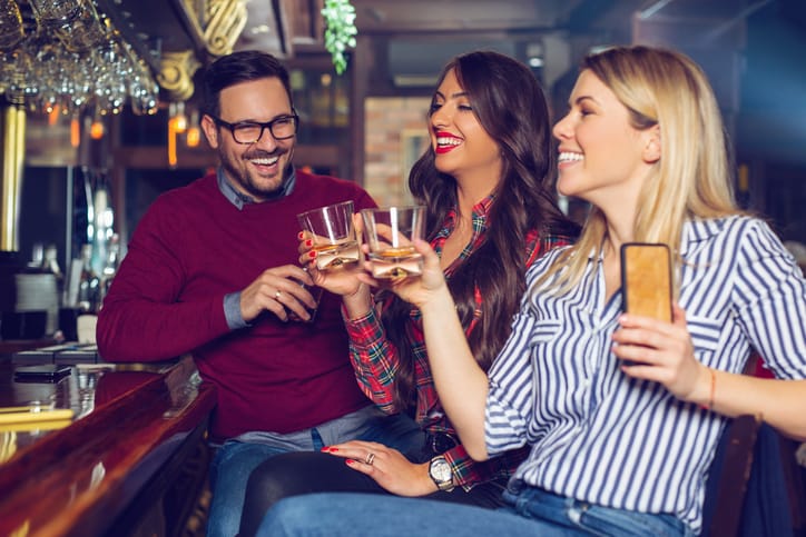 two women and man drinking at bar