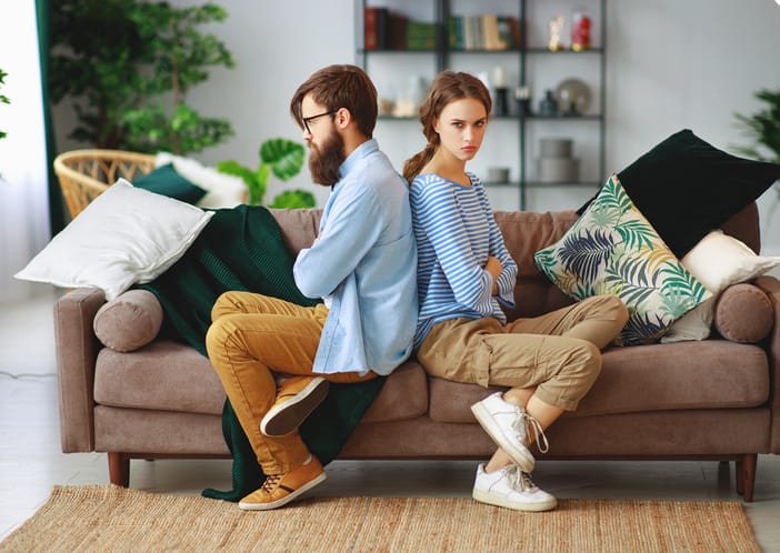 Couple in argument sitting back to back on couch.