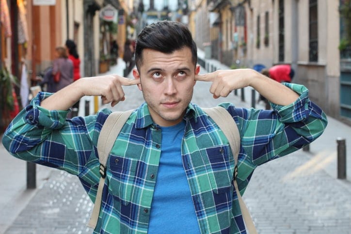 Man rolling his eyes and blocking his ears.