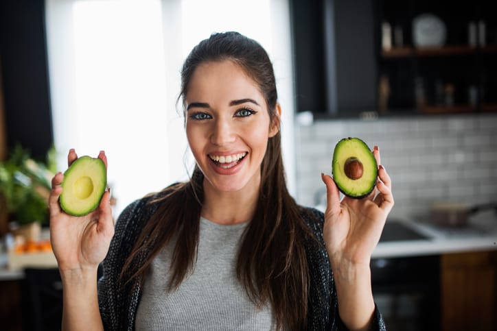Young woman holding an avocado.