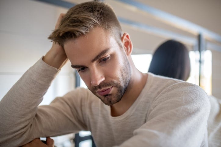 sad millennial man looking down