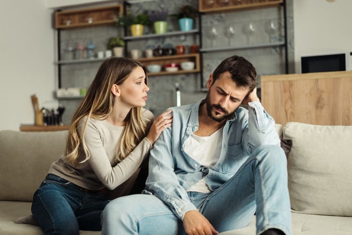 Young woman asking her boyfriend for forgiveness at home